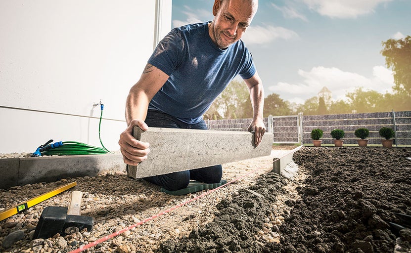 Muž kladie obrubníky trávnika v záhrade