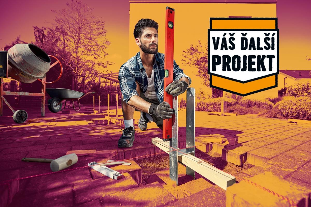 Remeselník vyrovnáva pätku stĺpika pomocou vodováhy na dláždenej terase.