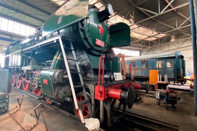 Zelená parná lokomotíva s červenou hviezdou v dielni.