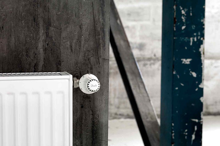 Radiátor s termostatickým ventilom pred tmavou stenou