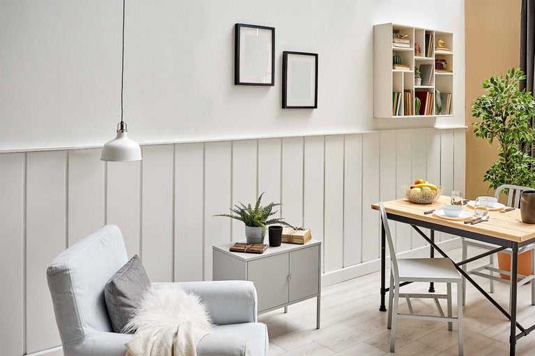 Obývacia izba s pohovkou, stolom, stoličkou, závesnou lampou a nástennou policou