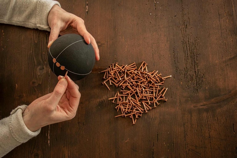 Dekoratívny nápad s čiernou guľou a klincami na drevenom stole