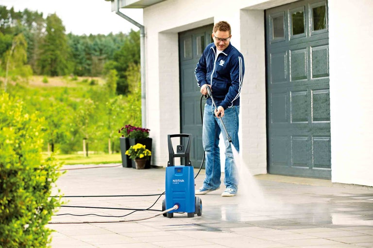 Muž čistí príjazdovú cestu pomocou vysokotlakového čističa Nilfisk