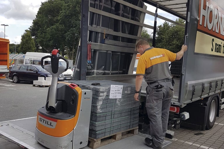 Zamestnanec spoločnosti Hornbach vykladá dlažobné kocky z nákladného automobilu pomocou vysokozdvižného vozíka.