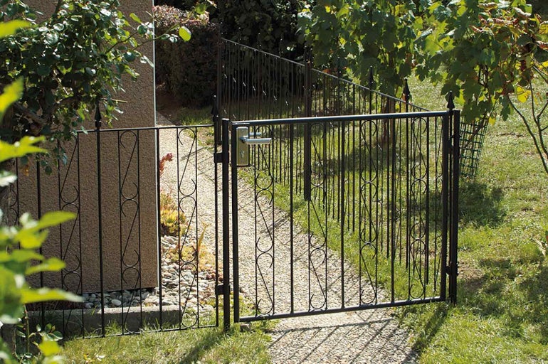Otvorená kovová záhradná bránka s kľučkou v záhrade