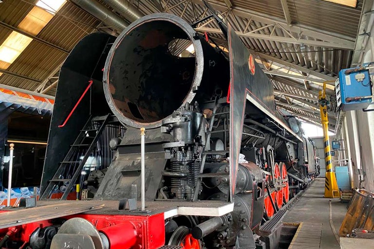 Stará parná lokomotíva stojí v dielni.