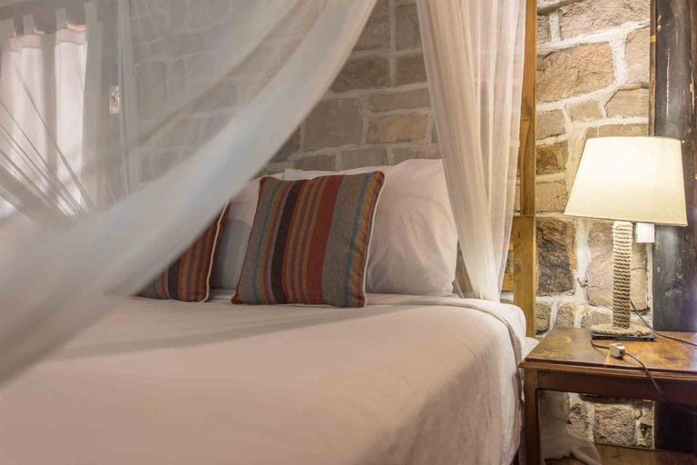 Spálňa s baldachýnom, pruhovanými vankúšmi a nočnou lampou