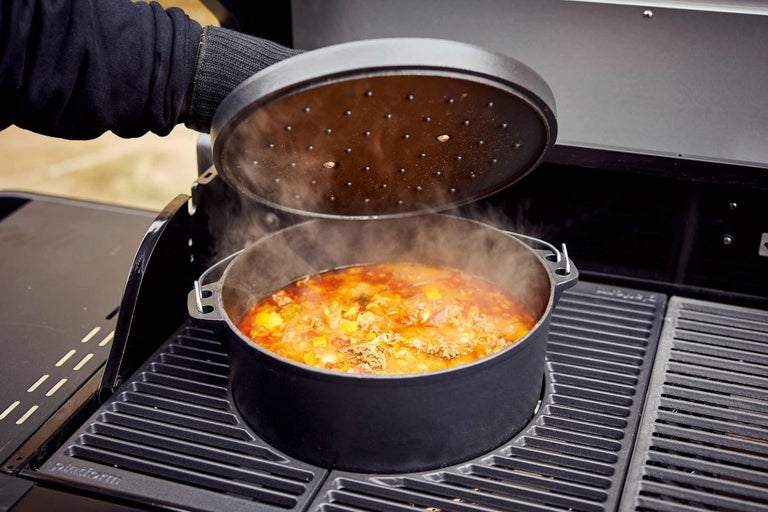 Na grile stojí a varí sa hrniec s pokrievkou.