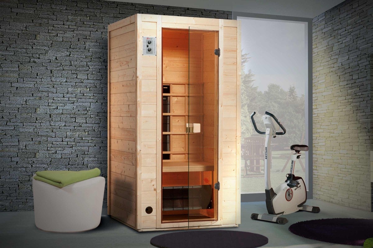 Drevená infra sauna so sklenenými dverami vedľa rotopedu