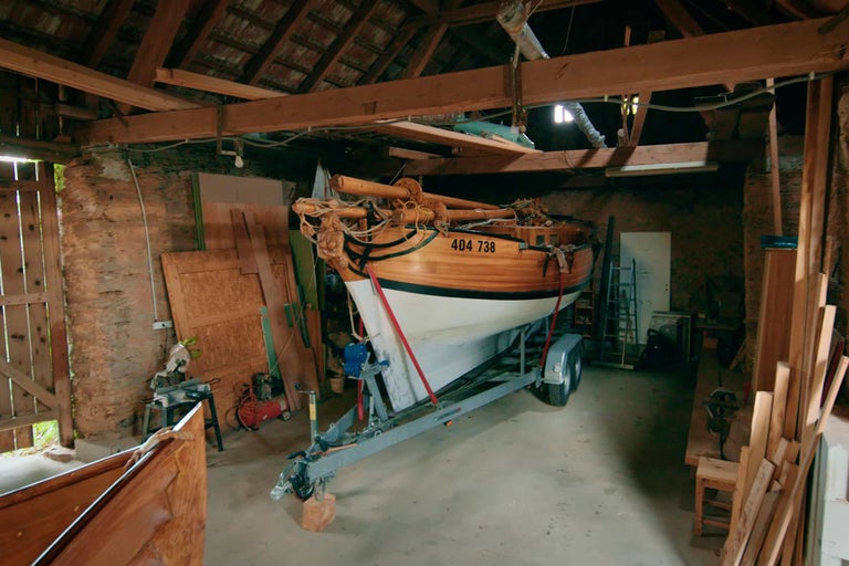 Interiérová fotografia dielne s drevenou plachetnicou na prívese