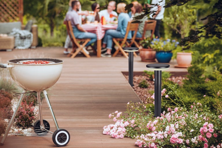 Scéna záhradného grilovania s guľovým grilom a solárnymi cestnými svetlami