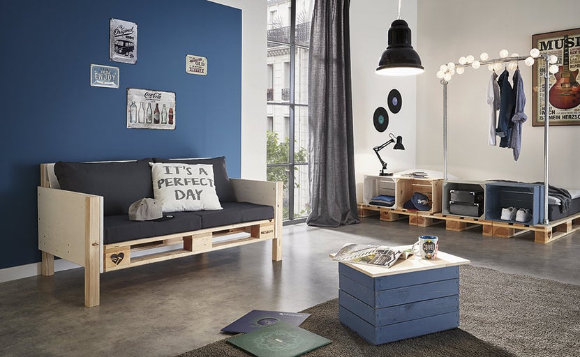 Obývacia izba s pohovkou z paliet, vešiakom na šaty a konferenčným stolíkom