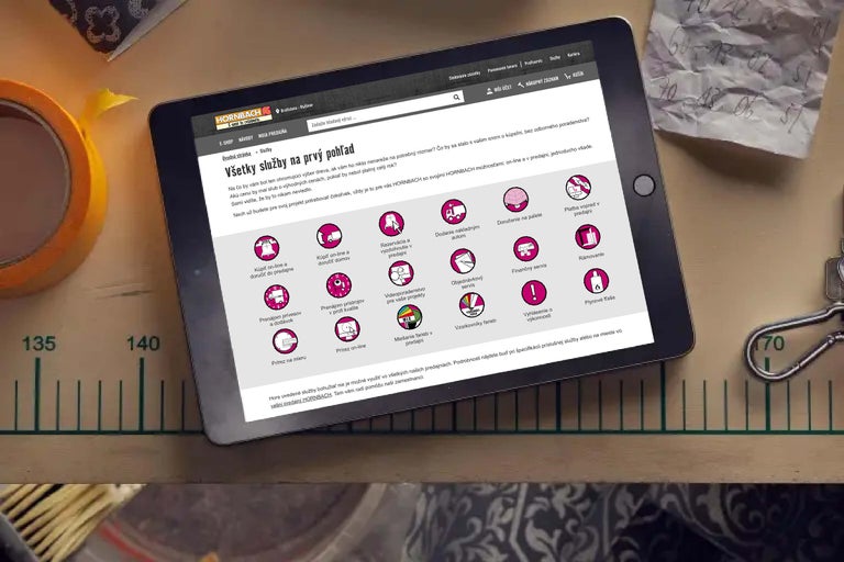 Na obrazovke tabletu sa zobrazuje stránka služieb Hornbach, ktorá zdôrazňuje rôzne služby, ako je rezanie, miešanie farieb a požičovňa strojov.