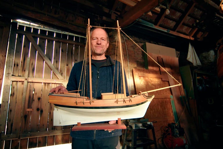 Muž drží drevený model lode