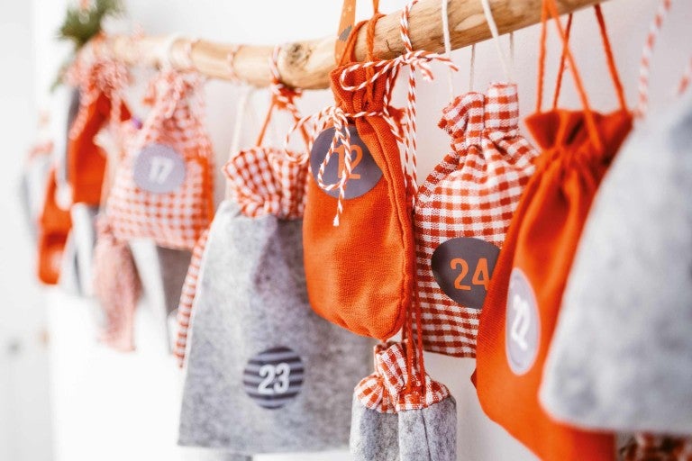 Adventný kalendár s látkovými vreckami zavesenými na konári