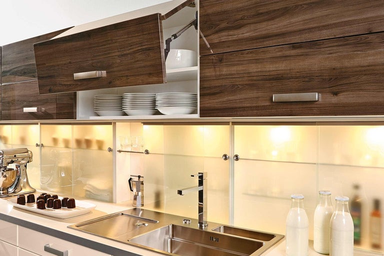 Kuchynská scéna s drezom, batériou, kuchynským robotom, skrinkami s dreveným vzorom a riadom