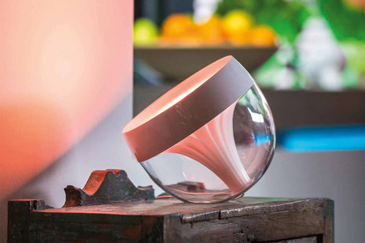 Stolná lampa Philips Hue Iris zo skla na drevenom stole