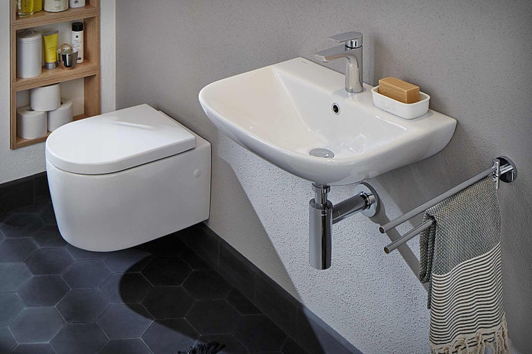 Moderná kúpeľňa s nástenným WC, umývadlom, batériou a držiakom na uteráky.