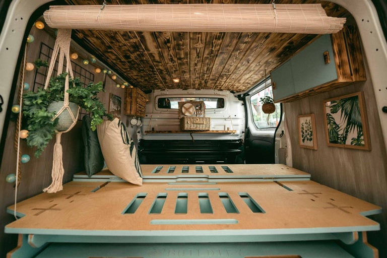 Interiér prestavanej dodávky s drevenou podlahou, posteľou a dekoráciou