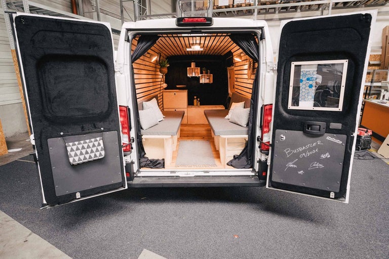 Interiér prestavanej dodávky s dreveným obkladom, posteľami a kuchynským kútom