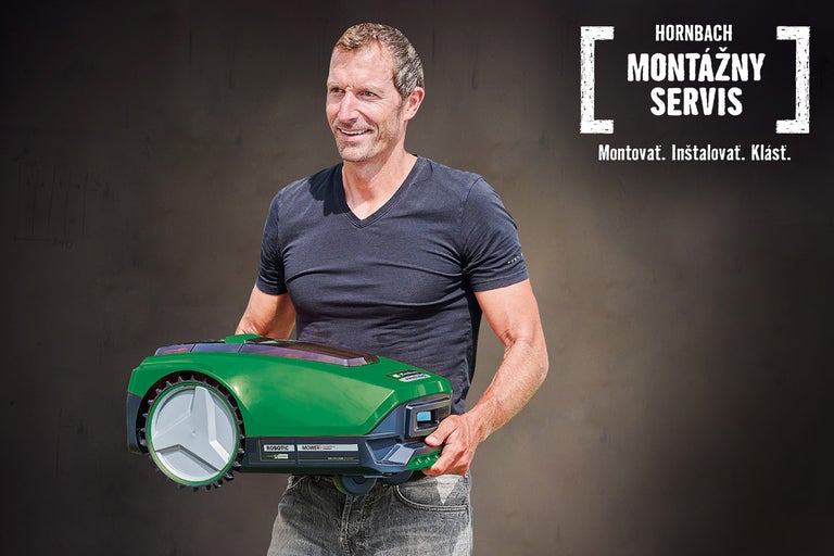 Muž drží zelenú robotickú kosačku MOWiT na pozadí montážneho servisu Hornbach.