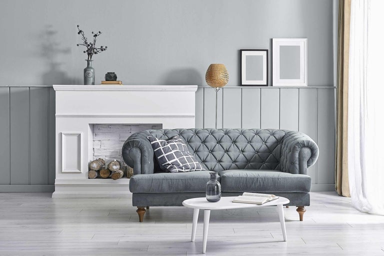 Obývacia izba so sivou pohovkou, krbom a bielym stolom