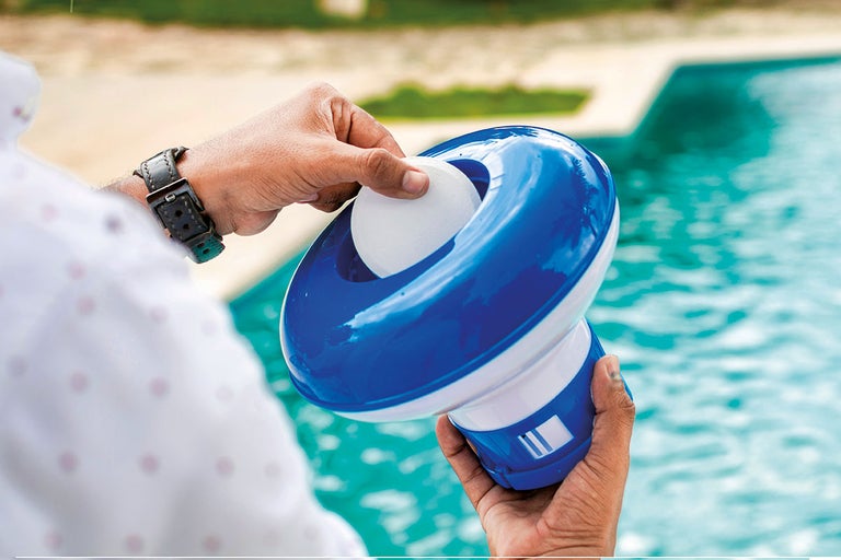 Osoba plní plávajúci dávkovač chlórovou tabletou