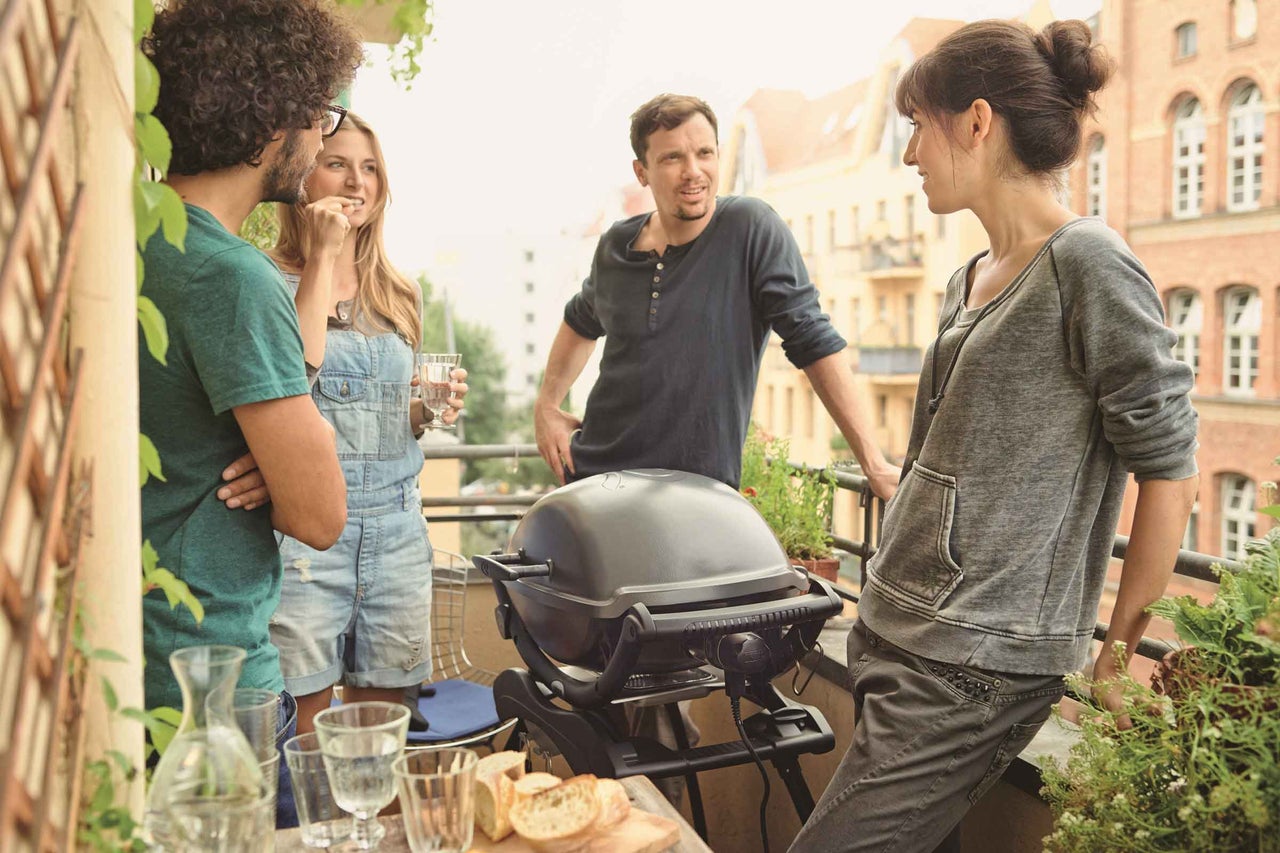 Ľudia grilujú na balkóne s elektrickým grilom.