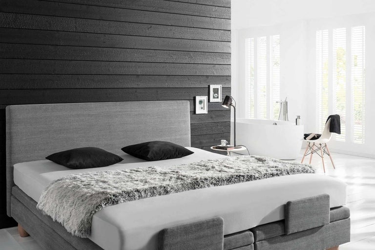 Spálňa s posteľou boxspring, nočnou lampou a vaňou v pozadí