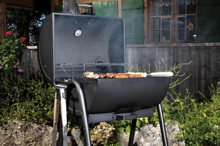 Otvorený gril na drevené uhlie s jedlom v záhrade