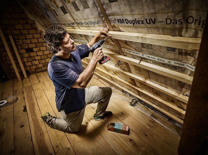 Remeselník pripevňuje parozábranu skrutkami na krov