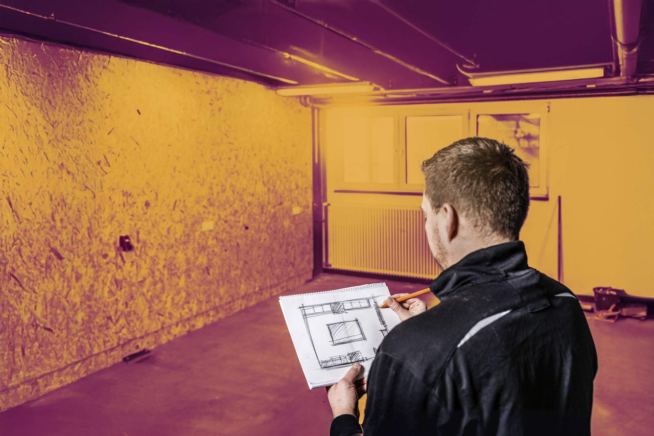 Muž s plánom v miestnosti s OSB doskami
