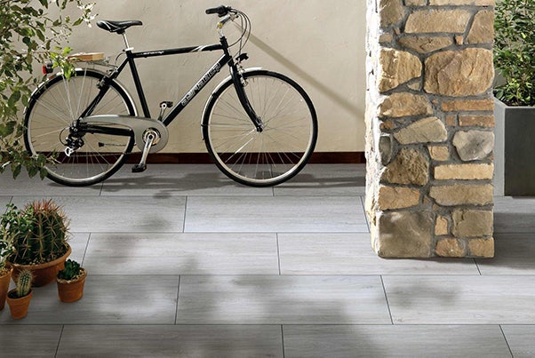 Dlaždicová podlaha s bicyklom, kamenným stĺpom a rastlinami