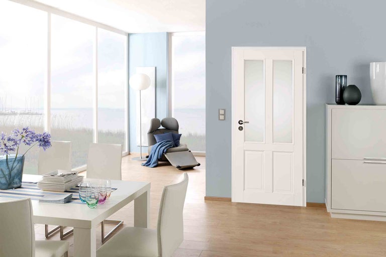 Interiér s jedálenským stolom, kreslom a interiérovými dverami so sklenenými vložkami.