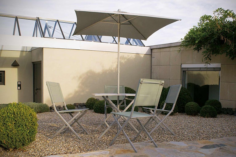 Záhradná scéna so stolom, stoličkami a slnečníkom na štrkovom povrchu