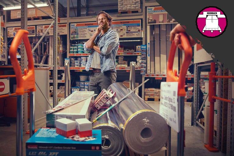 Muž s nákupným vozíkom plným stavebných materiálov v predajni Hornbach.