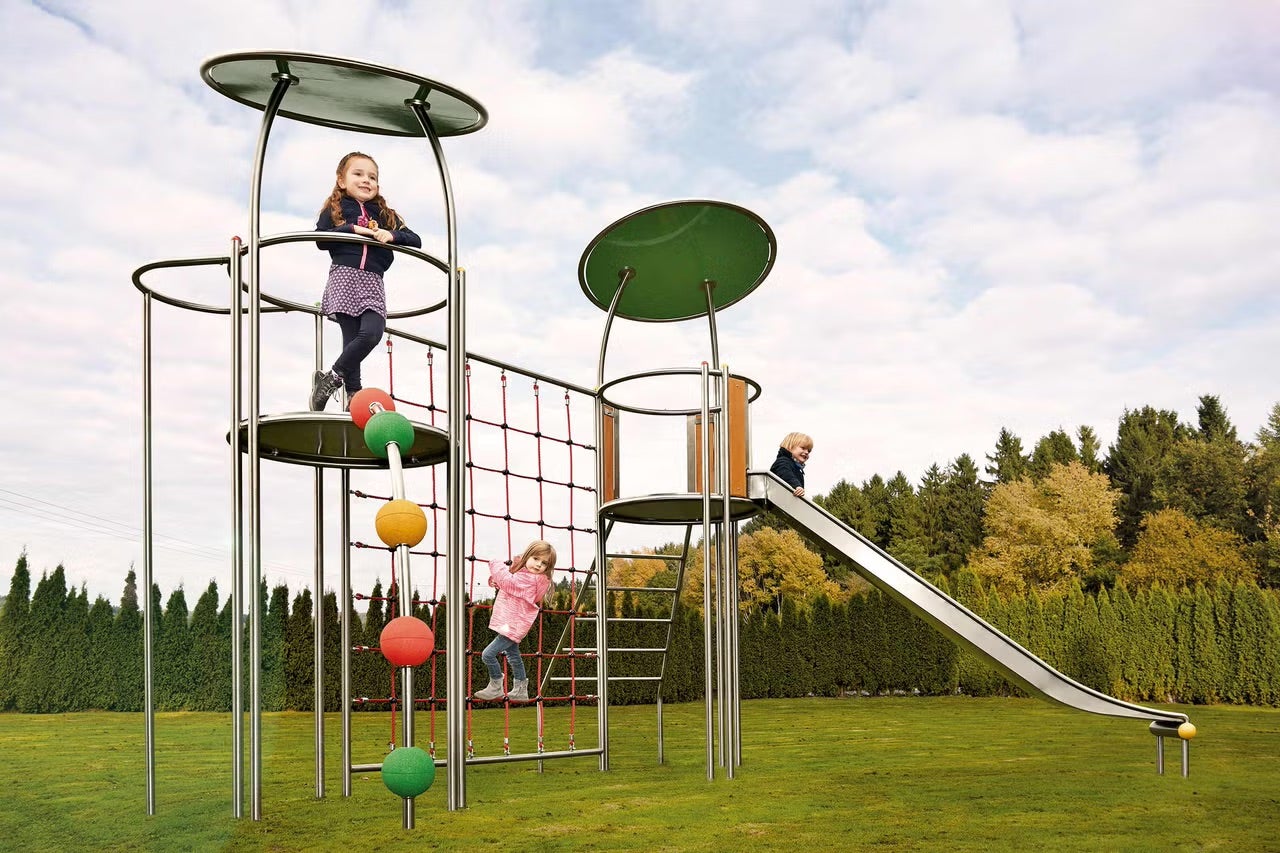 Detské ihrisko so šmýkačkou, lezeckou stenou a deťmi v záhrade.