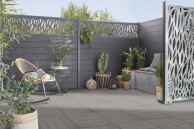 Upravený vonkajší priestor s prvkami na ochranu súkromia, terasovými dlaždicami a rastlinami.