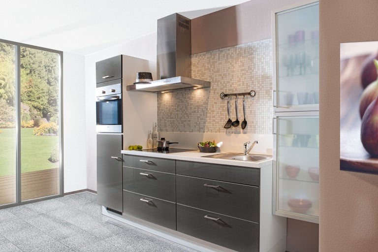 Svetlá kuchyňa so sivými skriňami, nerezovými spotrebičmi a výhľadom do zelene