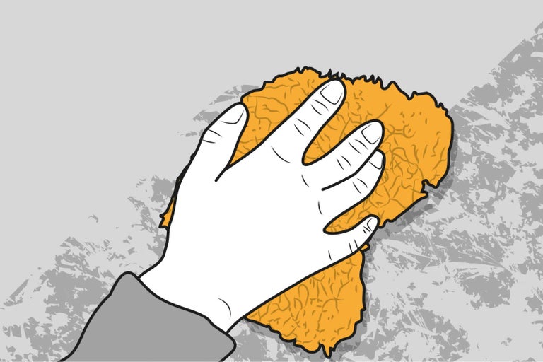 Ruka s hubkou čistí stenu.