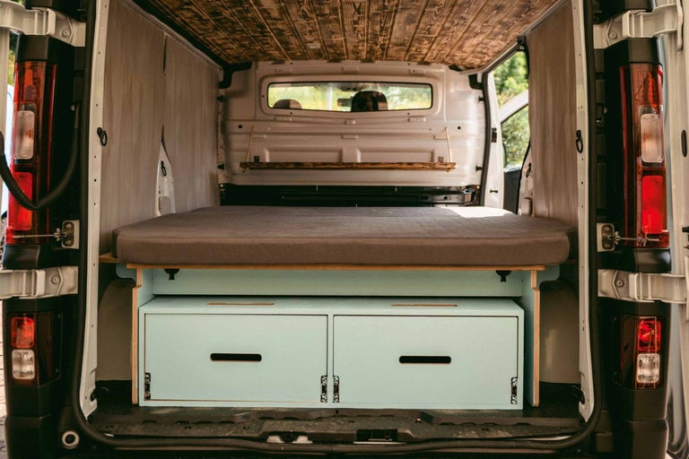 Interiér prestavanej dodávky s posteľou, zásuvkami a dreveným obložením