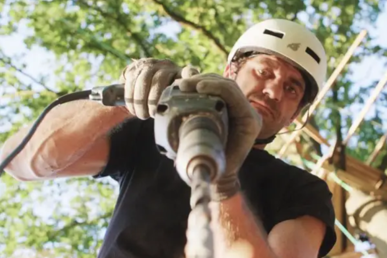 Muž s ochrannou helmou používa vŕtačku.