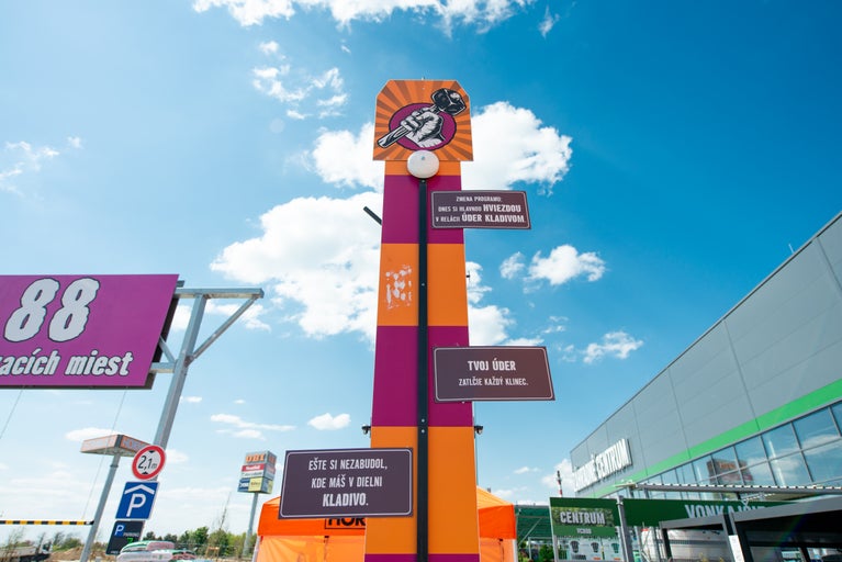 Reklamný stĺp v tvare silomera s kladivom pred predajňou Hornbach.