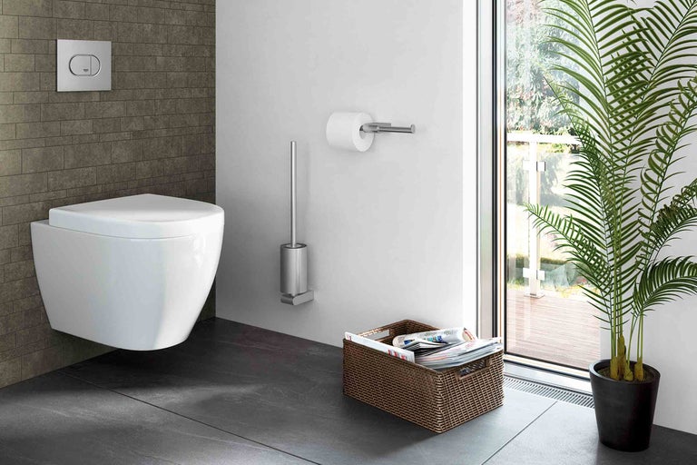 Moderná kúpeľňa s nástenným záchodom, ovládacím tlačidlom, držiakom toaletného papiera, WC kefou, držiakom na časopisy a izbovou rastlinou.