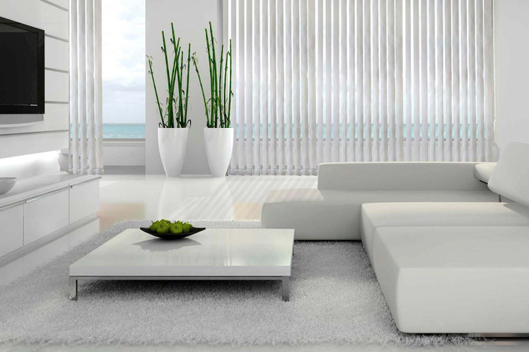 Moderná obývacia izba s pohovkou, konferenčným stolíkom, izbovými rastlinami a vertikálnymi žalúziami