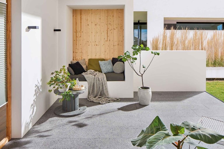 Terasa so sedacou časťou, ozdobnými vankúšmi, rastlinami a drevenými prvkami