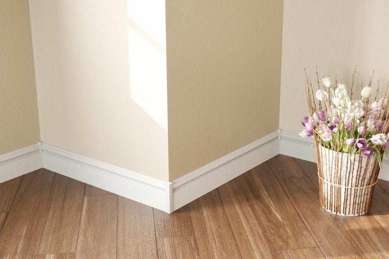 Roh miestnosti so soklovými lištami a kvetinovou aranžmánom na drevenej podlahe