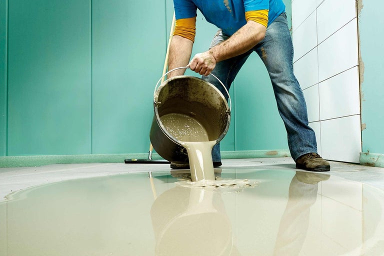 Muž leje poter z vedra na dlažbu.