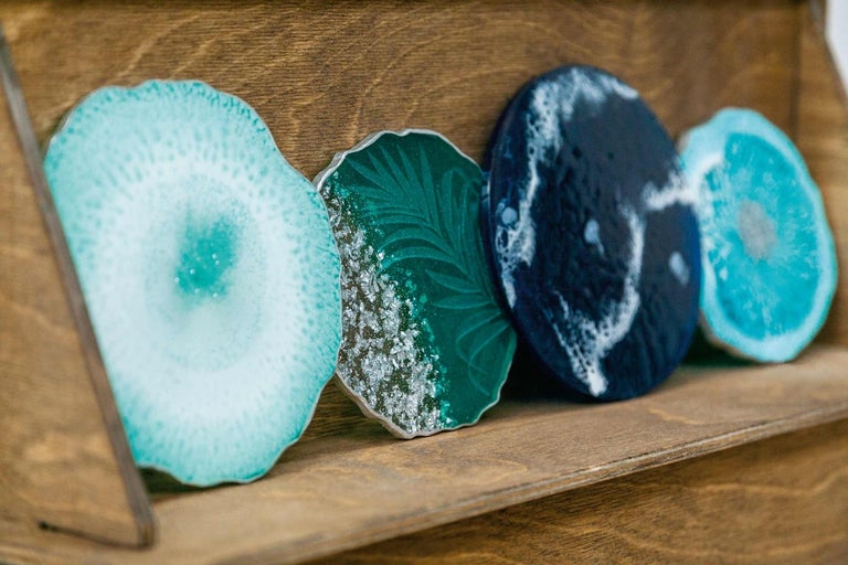 Štyri dekoratívne podložky zo syntetickej živice na drevenej polici.