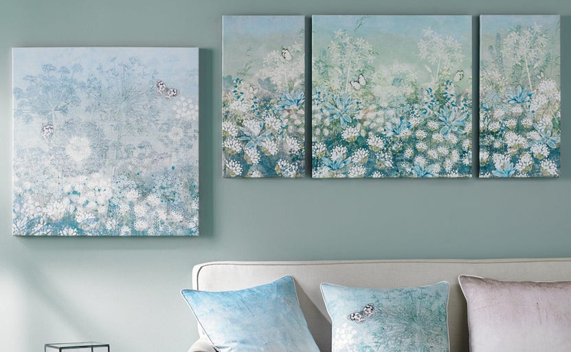 Obývacia izba s nástennými maľbami s kvetinovými a motýľovými motívmi nad pohovkou.